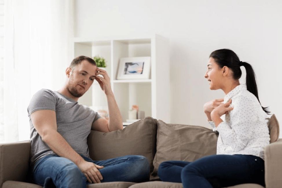 A man and a woman are sitting on a couch having a conversation.